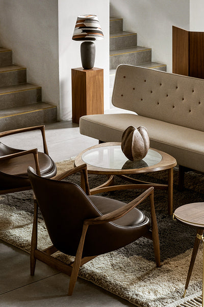 collection photo of two modern chairs flanking a small round green lacquer table with a a black sculpture on top. the wall behind the furniture has a window and is painted a greige color with a textured wood art piece hanging on it.  image 69